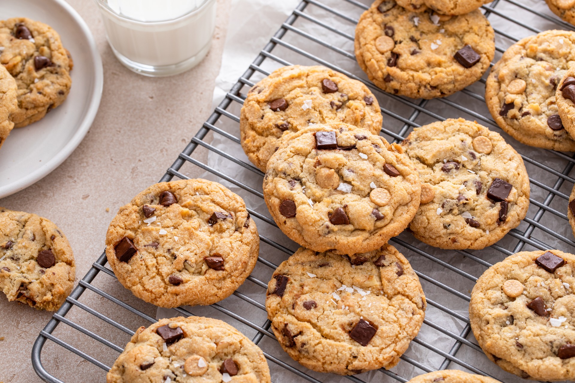 Chocolate chip cookies on a cooling rack with flaky salt served with milk